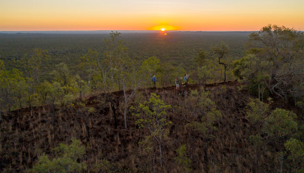 Aerial image of people walking the rim of the Kalkani Crater at sunset