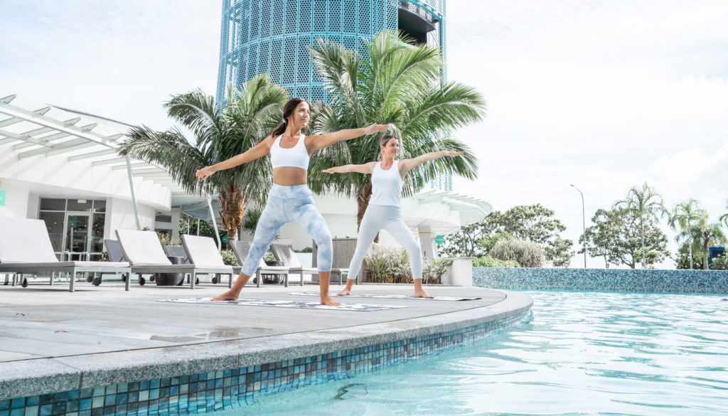 young women doing yoga next to the pool at at crystalbrook riley